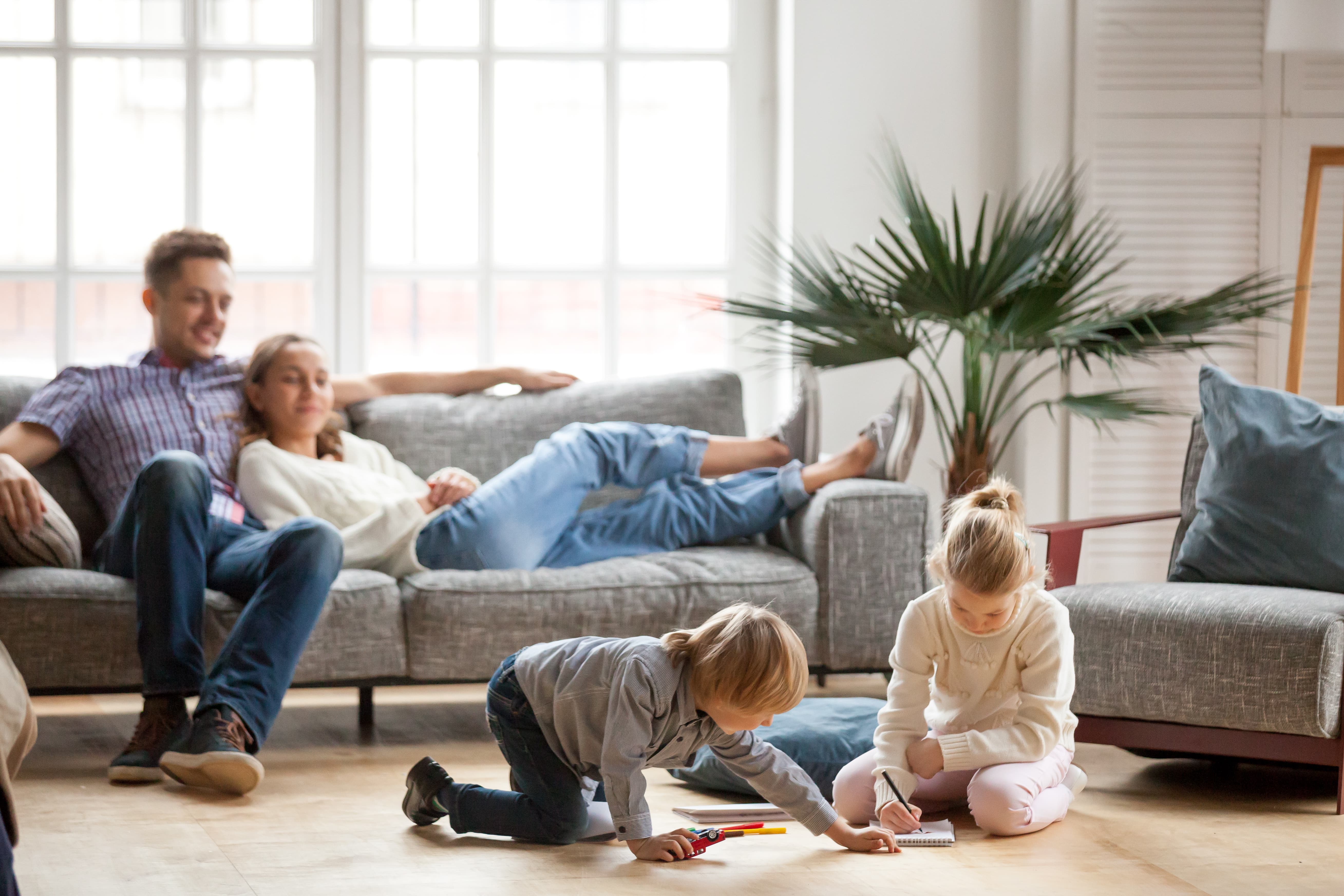 Ребенок наблюдает за родителями. Счастливая семья в квартире. Семья в гостиной. Семья на диване. Семья с детьми в гостиной.